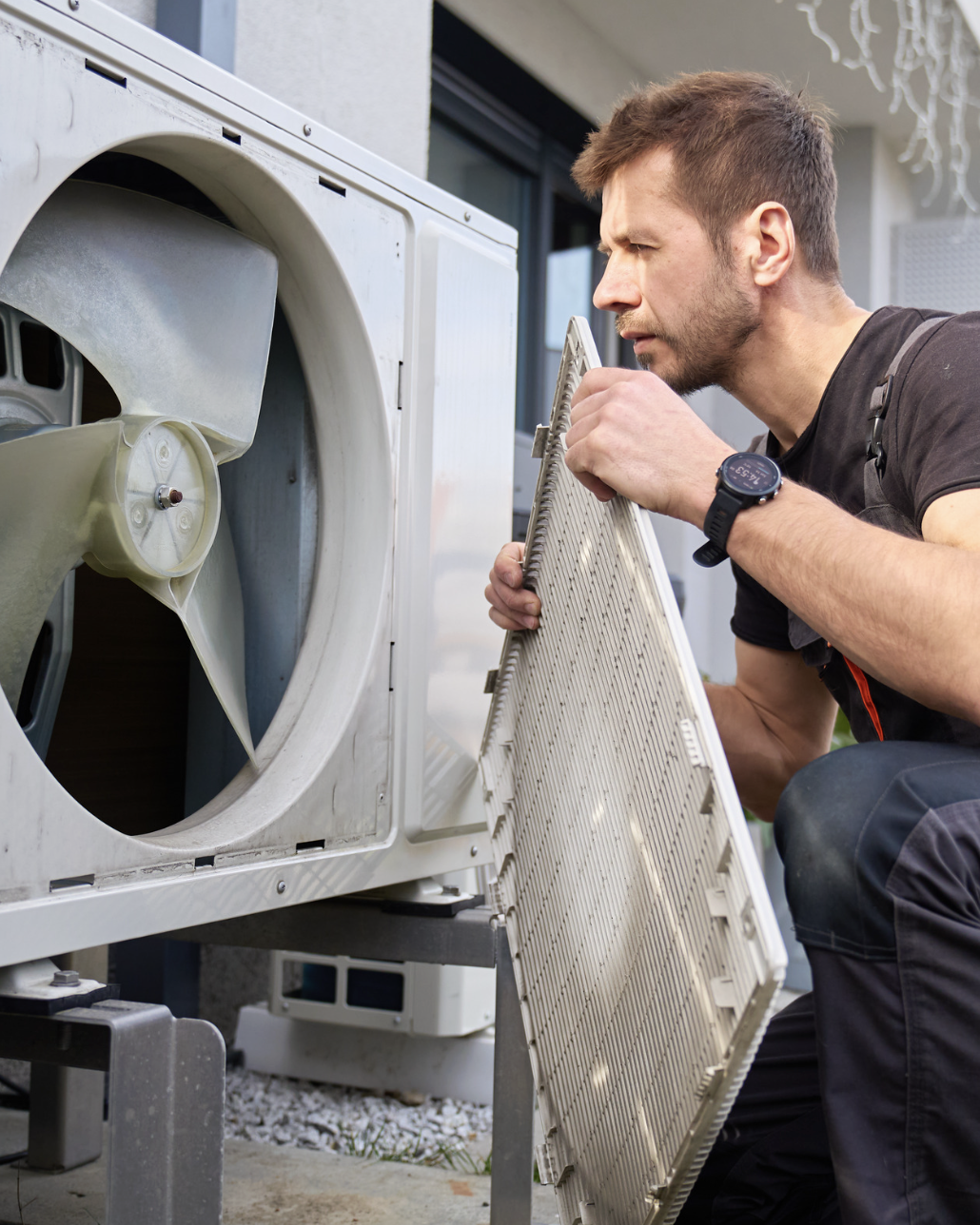 HVAC technician inspecting an outdoor condenser fan panel