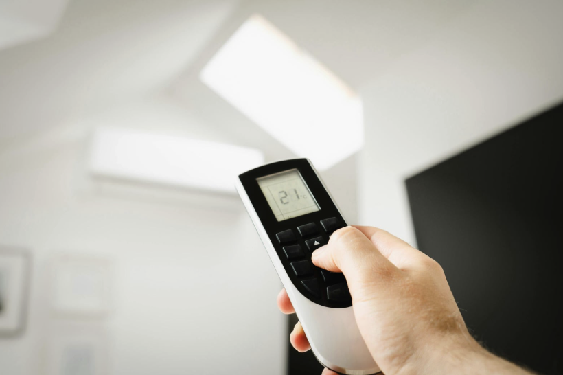 Hand using a remote to control a mini-split ductless A/C system