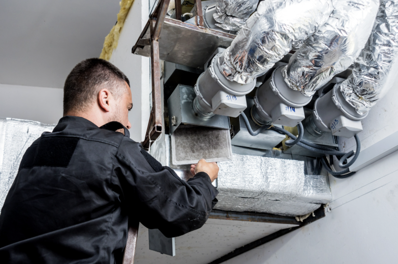 Technician servicing ductwork and air handler in a utility space